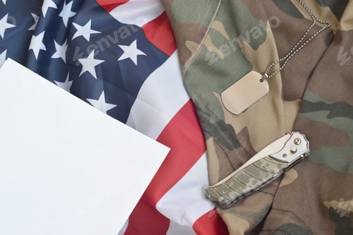 Preview: Army dog tag token and knife lies on Old Camouflage uniform and folded United States Flag.