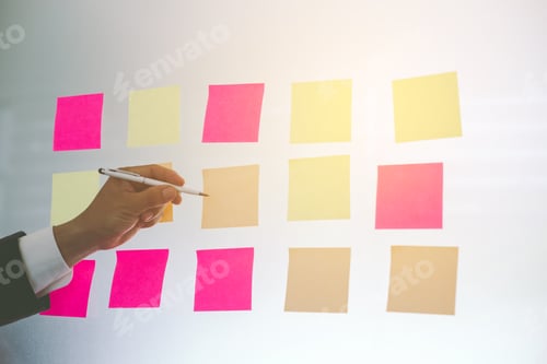 Preview: Close up hand businessman writing sticky notes on glass wall in office.