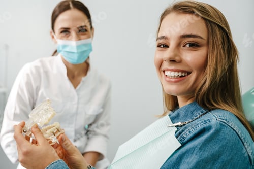 Preview: European mid happy dentist woman showing teeth imitation to her patient