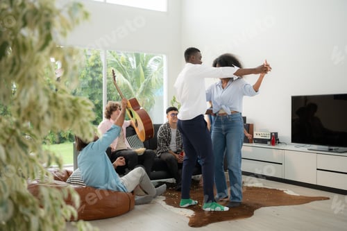 Preview: Group of multiethnic friends having fun at party by playing guitar, singing and dance together