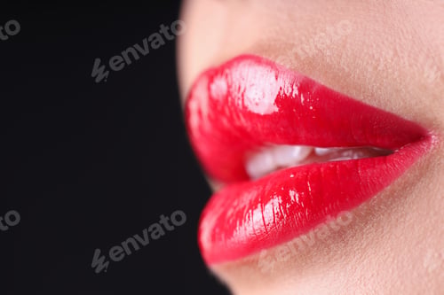 Preview: Woman with beautiful red lipstick on her lips against black background, macro view. Space for text