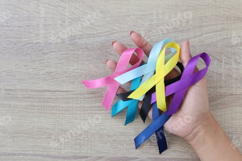 Preview: Colorful ribbons on palm hands on the wooden table, cancer awareness
