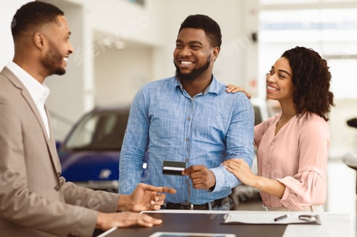 Preview: Couple Buying Car Giving Seller Credit Card In Dealership Office