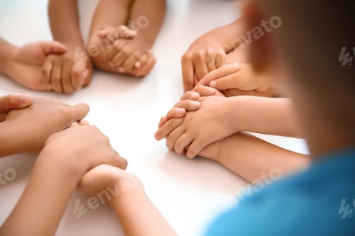 Preview: Little children holding hands at table, closeup. Unity concept