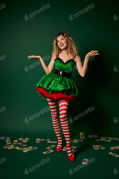 Preview: cheerful woman in green dress looking up and gesturing with money on floor, new year elf concept