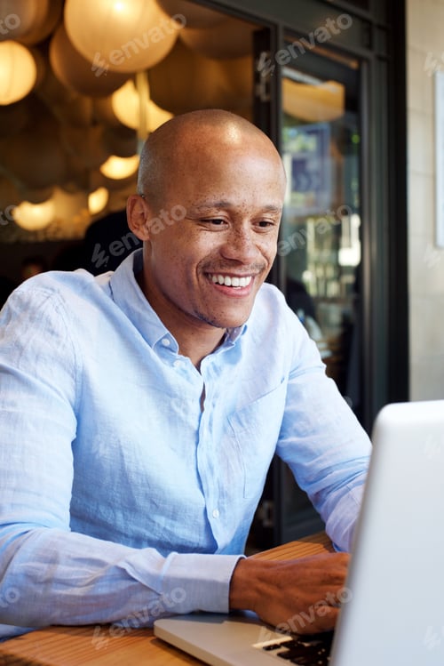 Preview: smiling african businessman working on laptop