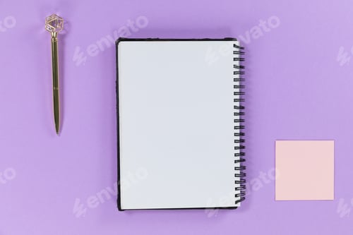 Preview: View of a notebook a pen and a small pink sheet of paper on plain purple background