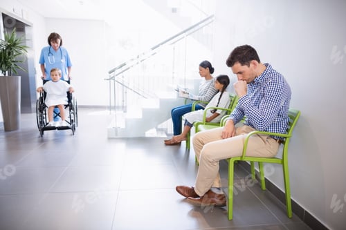 Preview: Man sitting on chair in hospital corridor