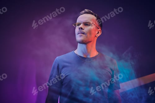 Preview: Handsome caucasian male model posing over neon colourful background in a studio