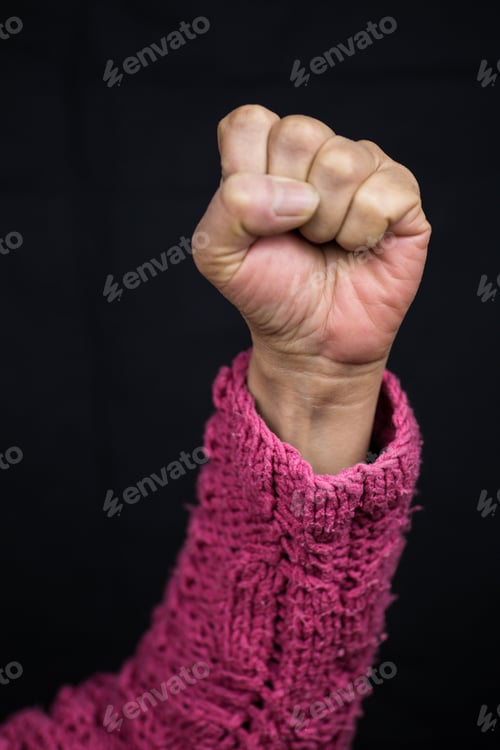 Preview: Vertical shot of an Asian female holding her fist as a sign of strength-women empowerment concept