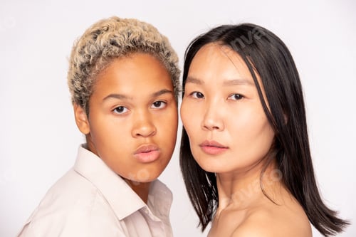 Preview: Faces of young friendly African and Asian females standing close to one another