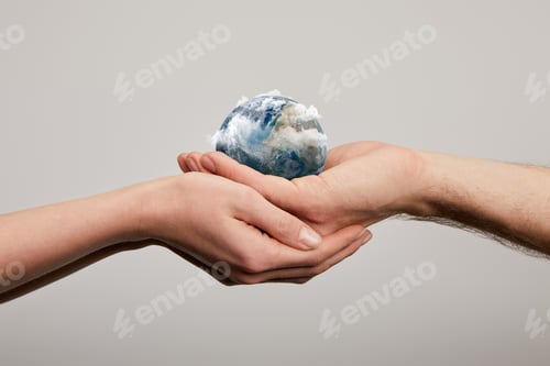 Preview: man and woman holding planet model on grey background, earth day concept