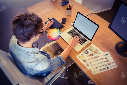 Preview: Happy designer working on his laptop in creative office
