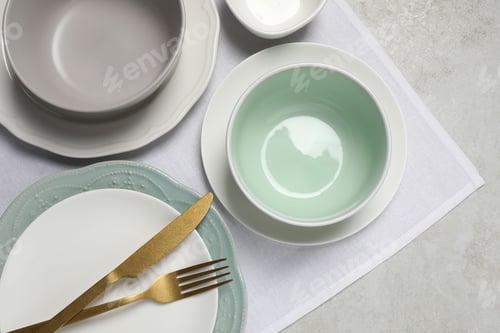 Preview: Beautiful ceramic dishware and cutlery on light grey table, top view