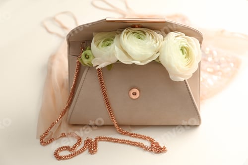 Preview: Stylish clutch bag and spring flowers on light background