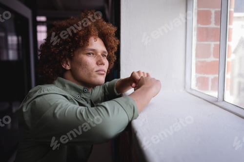 Preview: Portrait of mixed race businessman standing in office and looking at window