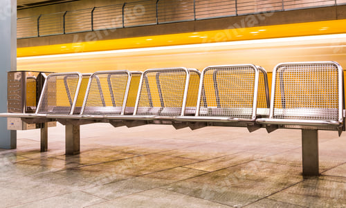 Preview: Yellow train speeding in subway underground behind metal waiting benches