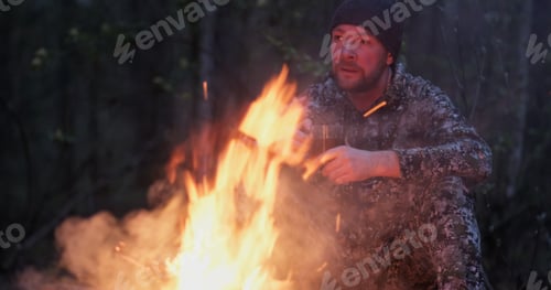 Preview: Adult man outdoors is cooking meal on fire. Man roasts sausages on a fire on nature.