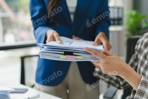 Preview: Business professionals exchanging important documents in office