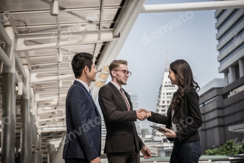 Preview: Business partner shaking hands and while meeting in front of office. Business success concept.