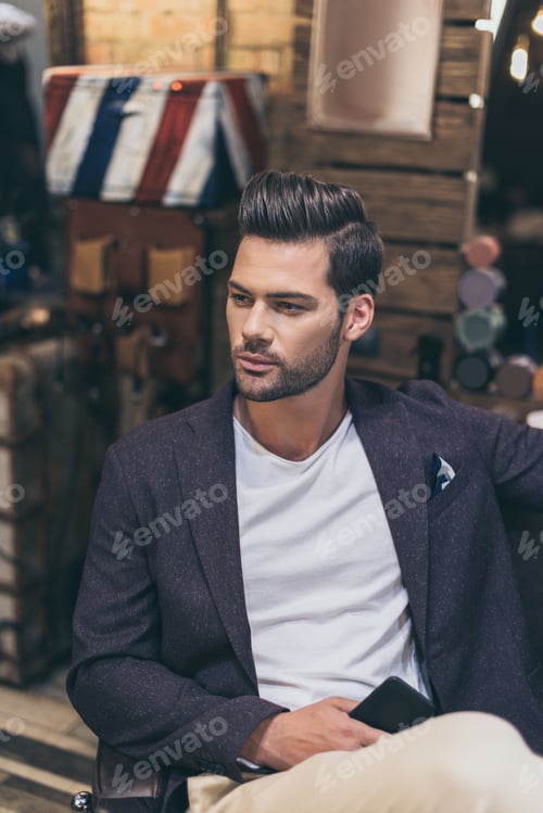 Preview: Portrait of handsome caucasian man with fashionable hairstyle at barber shop
