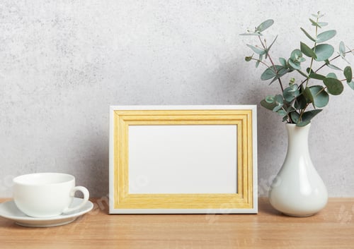 Preview: Empty photo frame, coffee cup and eucalyptus branches on table
