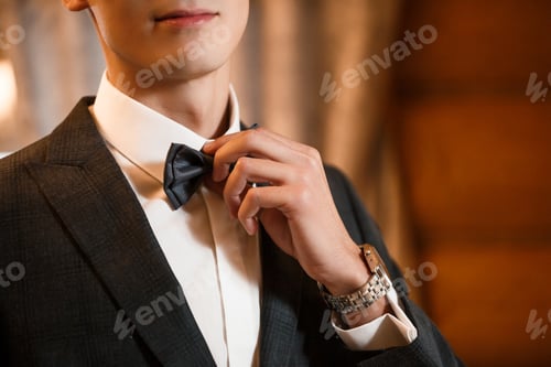 Preview: Elegant Man Adjusting Bowtie for Formal Occasion