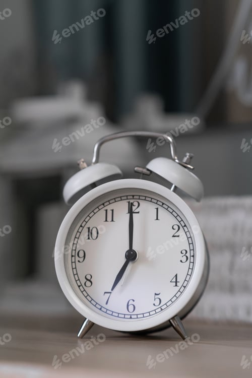 Preview: Close-up of a round white alarm clock on a table in the bedroom.