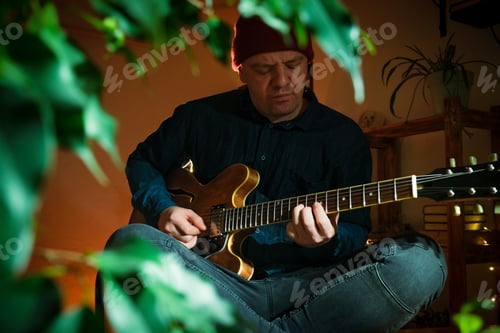 Preview: Man Playing Electric Guitar Indoors Under Soft Lighting