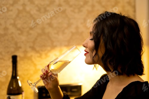 Preview: A young beautiful woman enjoys a glass of champagne. close-up portrait