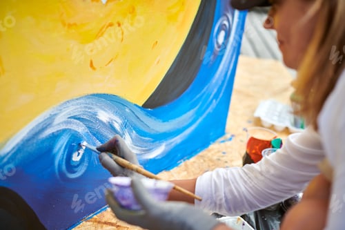 Preview: Female painter draws picture with paintbrush on canvas for outdoor street exhibition
