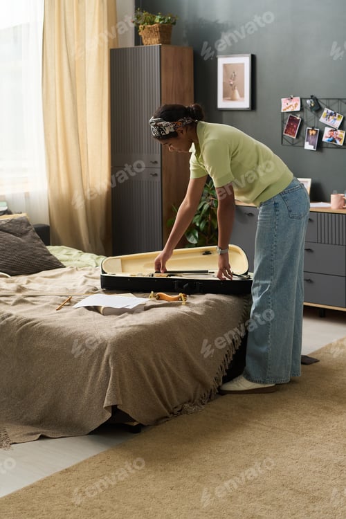 Preview: Teenage Girl Packing Suitcase in Cozy Bedroom Setting