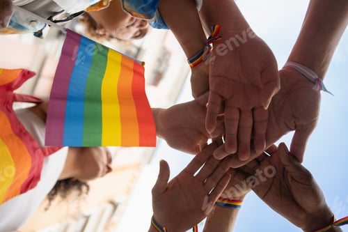 Preview: Homosexual people holding hands and a rainbow flag.Unity and support for the LGBTQ+ community