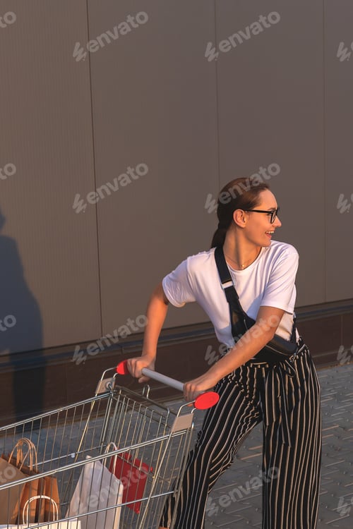 Preview: Beautiful young girl with paper bags with purchases near the shopping mall in the sunlight with supe