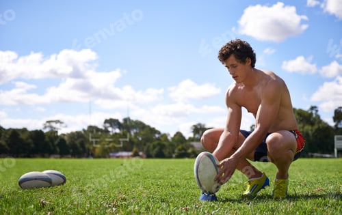 Preview: Preparing for a kick. A young rugby player preparing for a kick on a sports field.