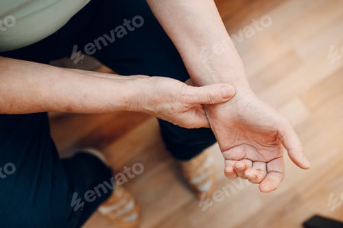 Preview: Female old hand measuring her own arm pulse. Elderly woman heart health.
