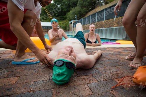 Preview: Lifeguards and friends looking at unconscious man at poolside