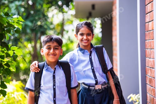Preview: Indian Cheerful school kids in uniform smile at camera while standing outdoors on a sunny school day