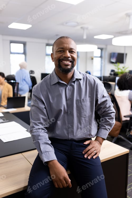 Preview: Vertical image of happy african american businessman looking at camera in office