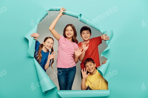 Preview: Smiling interracial kids in casual clothes waving hands at camera during international children day