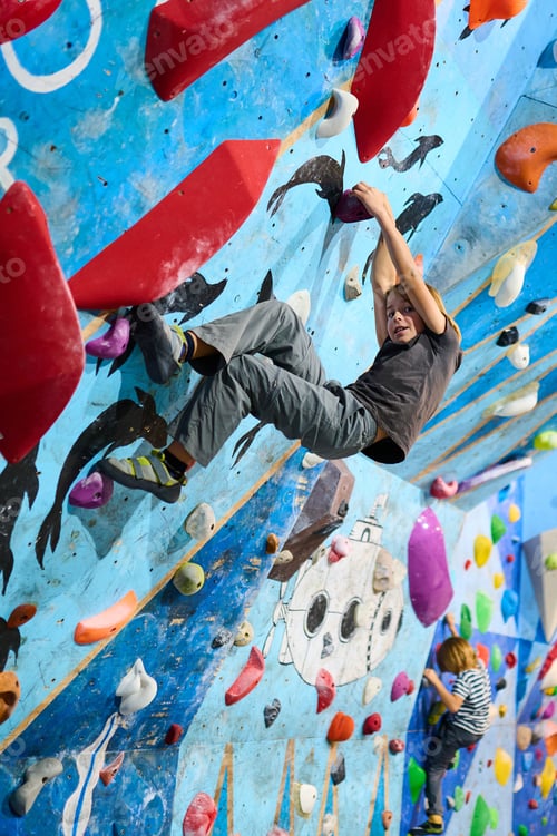 Preview: A 10-year-old boy climbing on a colorful indoor bouldering wall, focused on reaching the next hold