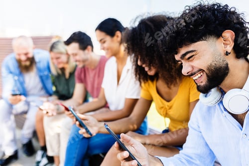Preview: Group of young people using mobile phone in city street