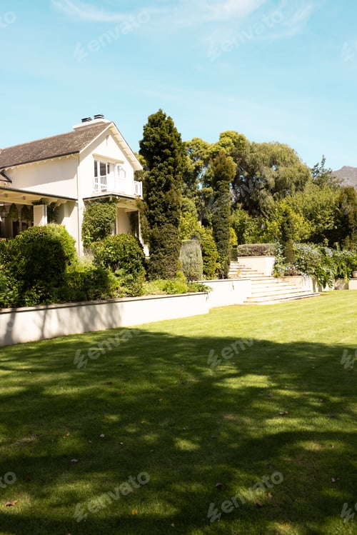 Preview: Lush green lawn leads up to large white house with trees at home