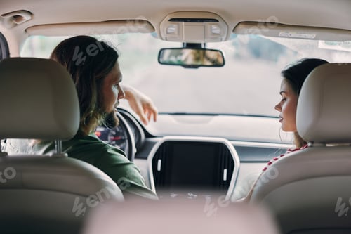 Preview: Young couple talking while driving in a car, showcasing a relaxed atmosphere and connection between