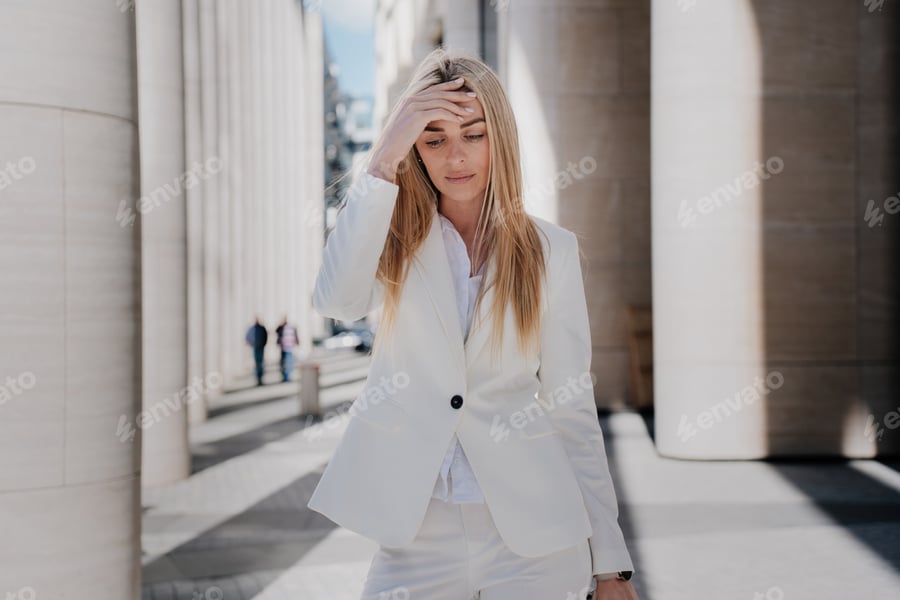Cover for Frustrated young woman walking eyes looks down with upset facial expression touching head,