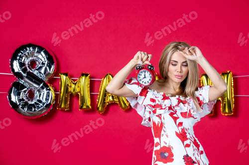 Preview: front view young female in cute dress holding clock on red background sensual horizontal feminine