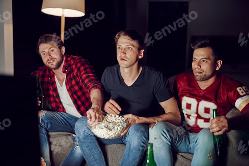 Preview: Focused men watching footaball match in the evening