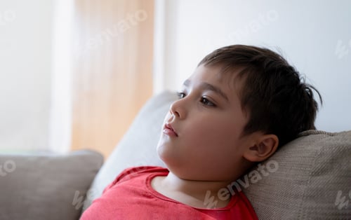 Vista previa: Close up face kid with curious face, Portrait Child sitting on couch looking out deep in thought