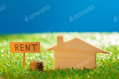Preview: Wooden toy house with rent sign on grass