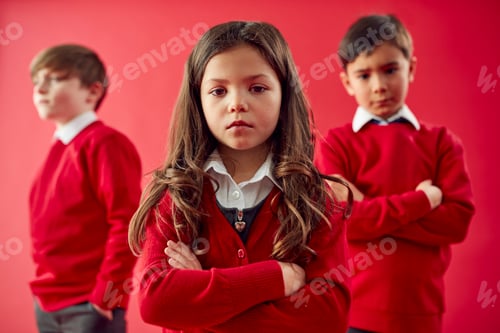 Preview: Group Of Elementary School Pupils Wearing Uniform Folding Arms Against Red Studio Background